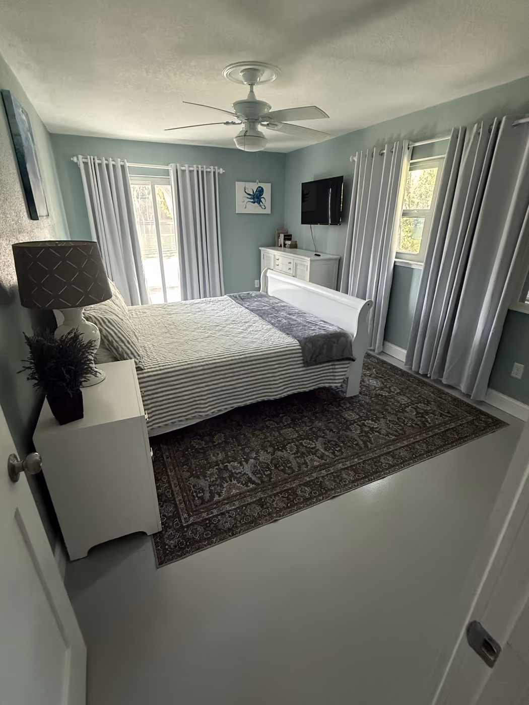 Bedroom with new curtain rods and curtains hung over the windows and slider