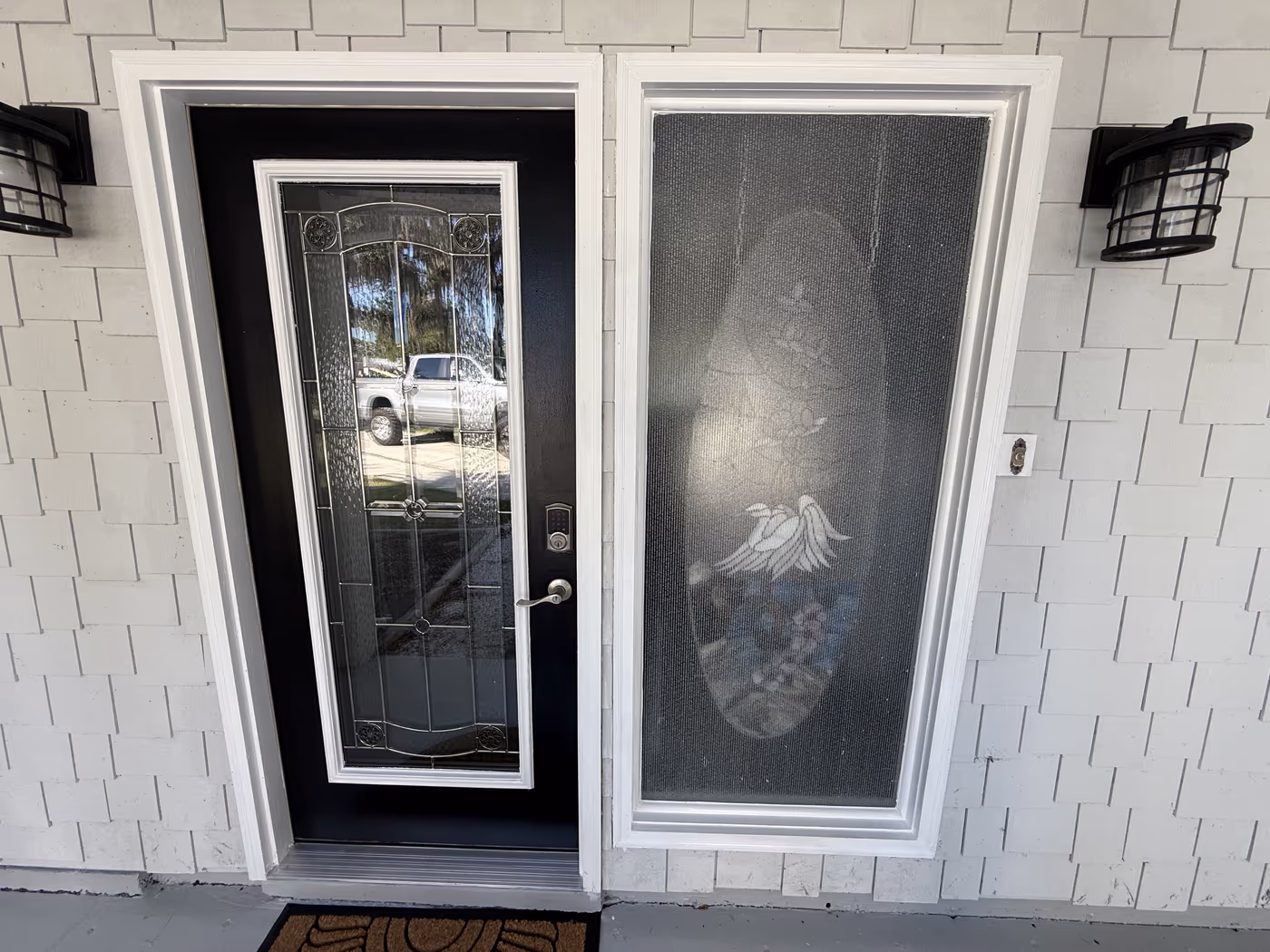 Black front door with leaded glass, new white trim, and porch lighting