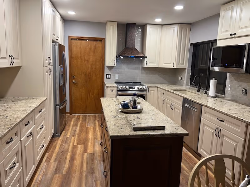 Same kitchen remodeled with white cabinets, quartz counters, and a wood island