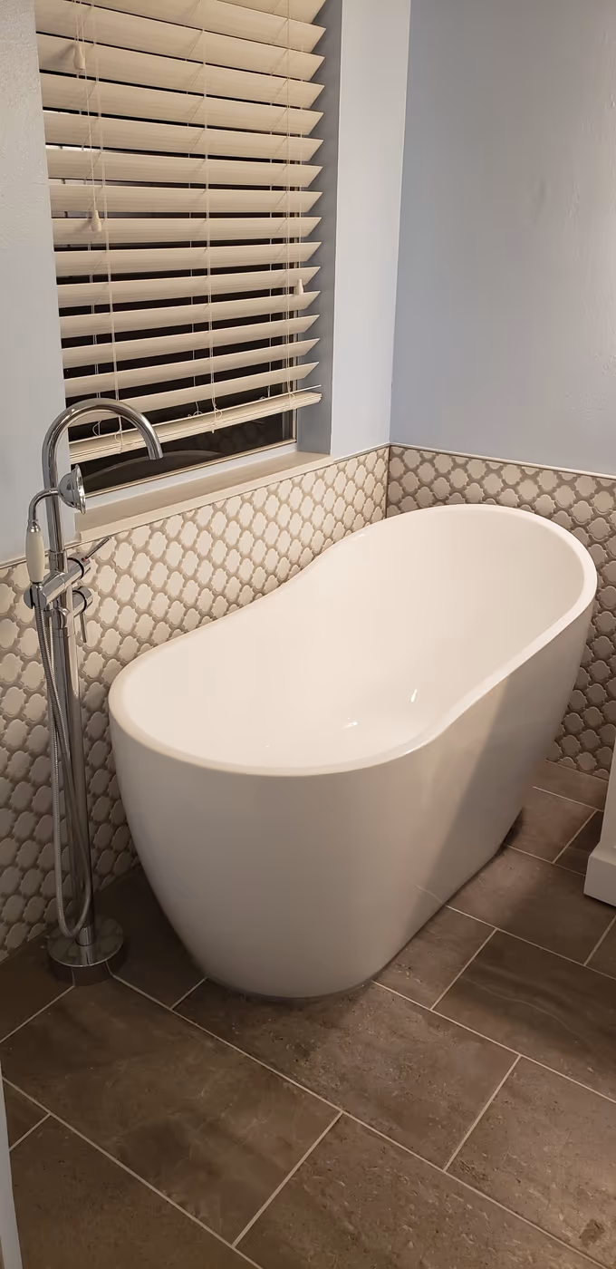 Freestanding soaker tub with a new tile accent wall and floor tile